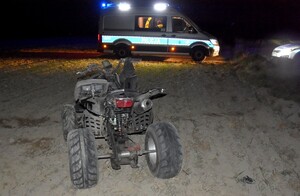 Zatrzymany Quad, a w tle radiowóz z włączonymi światłami błyskowymi.