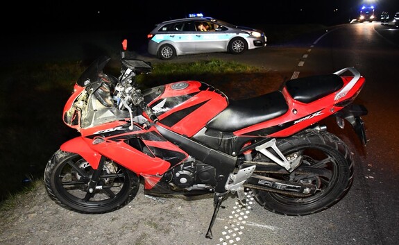 Motocykl na miejscu zdarzenia. W tle radiowóz policyjny.