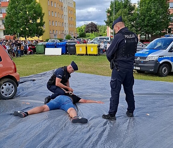 Festyn - Służby Mundurowe Dzieciom. Pokaz, policjant obezwładnia groźnego przestęcę.