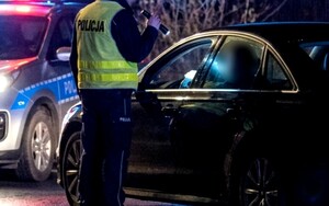 Policjant kontroluje w nocy auto.