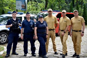 Zdjęcie grupowe policjantów i strażaków. W tle pojazdy służbowe mundurowych.