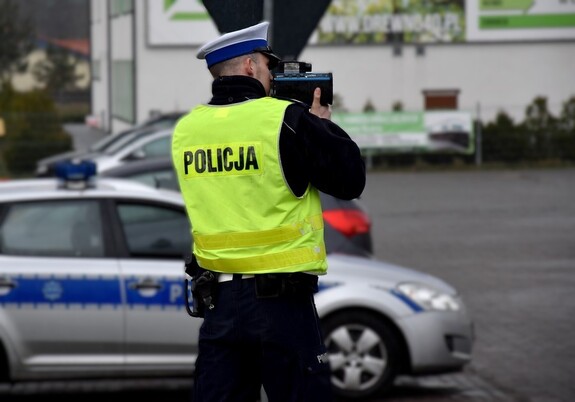 Policjant z drogówki mierzy prędkość pojazdów.