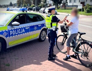 Policjant podczas działań kontroluje osobę poruszającą się rowerem.