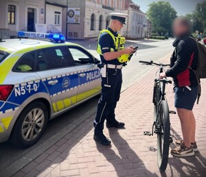 Policjant podczas działań kontroluje osobę poruszającą się rowerem.