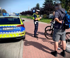Policjant podczas działań kontroluje osobę poruszającą się rowerem.