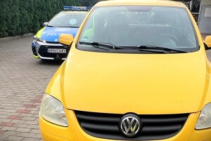 Żółty volkswagen, a w tle radiowóz policyjny.