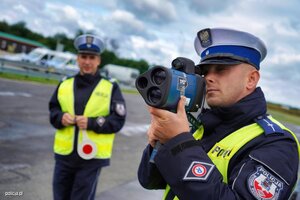 Policjanci podczas kontroli prędkości. Funkcjonariusz z ręcznym miernikiem prędkości.